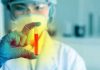 Scientist holding a test tube with red liquid in a laboratory setting