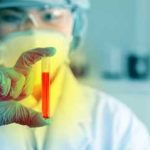 Scientist holding a test tube with red liquid in a laboratory setting