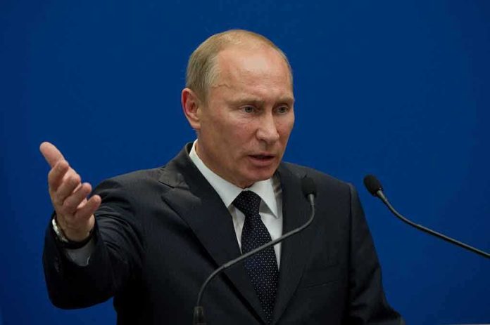 A man in a suit gesturing while speaking at a podium with microphones against a blue background