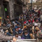 Skid Row Cash-For-Votes Shock A large group of people sitting on a city street, some wearing masks