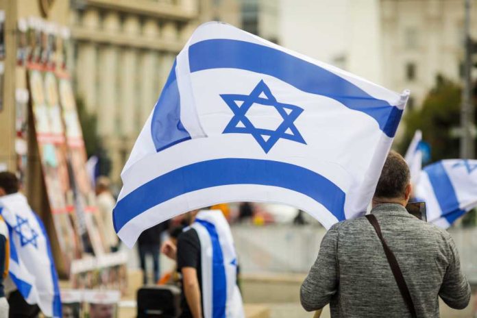 shutterstock_2385090811 Person holding an Israeli flag at a public demonstration