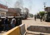 Scene of urban conflict with military vehicles and overturned cars