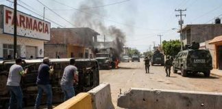 Scene of urban conflict with military vehicles and overturned cars