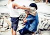 two children handling wooden planks at a work site