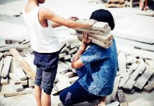 two children handling wooden planks at a work site