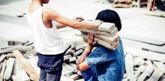 Children Trapped as Haiti Falls to Gang Violence two children handling wooden planks at a work site