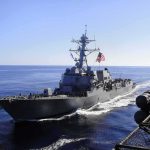 America’s Iran Campaign Shows No Signs of Slowing naval destroyer sailing at sea with flag flying
