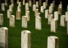 Rows of gravestones in a cemetery surrounded by green grass
