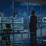The Global AI Race Just Got More Competitive Trader in a dark office with multiple stock monitors and city skyline at night