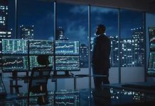 Trader in a dark office with multiple stock monitors and city skyline at night