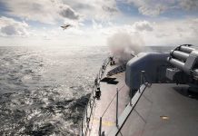 naval warship firing deck gun at sea
