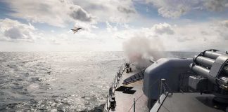 naval warship firing deck gun at sea