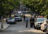 Police officers secure a residential street with patrol cars and yellow tape