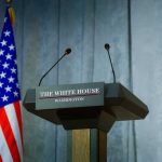 A New Trump $1 Coin Is Fueling a Legal Firestorm Press podium with the White House sign and an American flag in the background