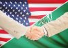 Handshake between two people over U.S. and Saudi flags