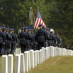 America’s Iran War Toll Continues to Climb Military honor guard marches through a cemetery with flags