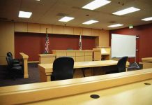 Interior view of an empty courtroom with wooden furniture and American flags
