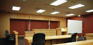 From Chart-Topping Star to Murder Trial Interior view of an empty courtroom with wooden furniture and American flags