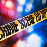 yellow crime scene tape with blurred police lights