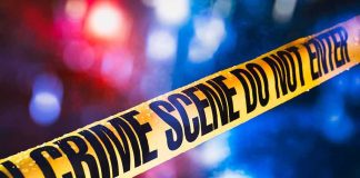 yellow crime scene tape with blurred police lights