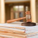 judge's gavel resting on a stack of case files