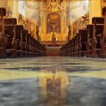 Church interior with wooden pews facing ornate altar
