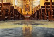 Church interior with wooden pews facing ornate altar