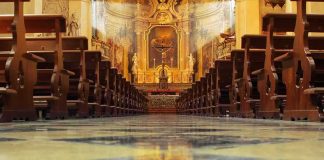 Church interior with wooden pews facing ornate altar