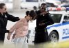 Police officers detain a woman beside a patrol car