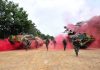 Soldiers running with armored vehicles through red smoke