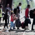 Border Showdown Escalates — EU Line Tested People with bags walking along railway tracks