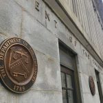 U.S. Treasury building exterior with bronze seal on stone wall