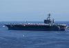 Aircraft carrier at sea with crew lining the deck