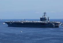 Aircraft carrier at sea with crew lining the deck