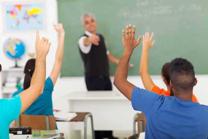 shutterstock_141891325 Students raising hands in a classroom while teacher points