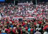 Crowd at a political rally facing a podium