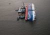 Capsized cargo ship with salvage vessels alongside