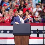Speaker at podium addressing a rally crowd