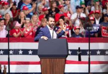 Speaker at podium addressing a rally crowd