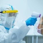 Congo’s Ebola Fight Is Running Out of Time — and Resources Healthcare worker in PPE checks patient temperature with infrared thermometer