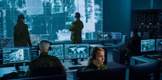 Military analysts monitor data on multiple screens in a command center