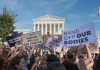 Protesters with signs outside a neoclassical courthouse