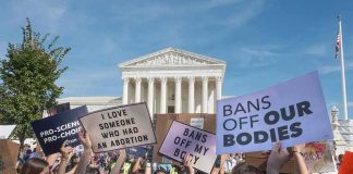Protesters with signs outside a neoclassical courthouse