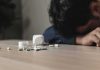 Person with head down near scattered pills on a table