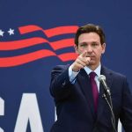 man in suit pointing while speaking at podium