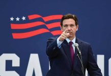 man in suit pointing while speaking at podium