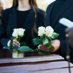 Jorge Messi Dies at 68, Leaving Lionel Messi and Soccer World in Mourning Mourners holding white roses beside a wooden casket