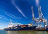 Container ship docked at port with cranes loading cargo