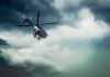 Police helicopter flying under dark storm clouds