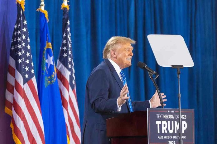 Person speaking at podium with flags in background.